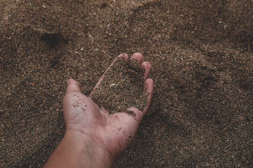 a person holding dry soil in their hands